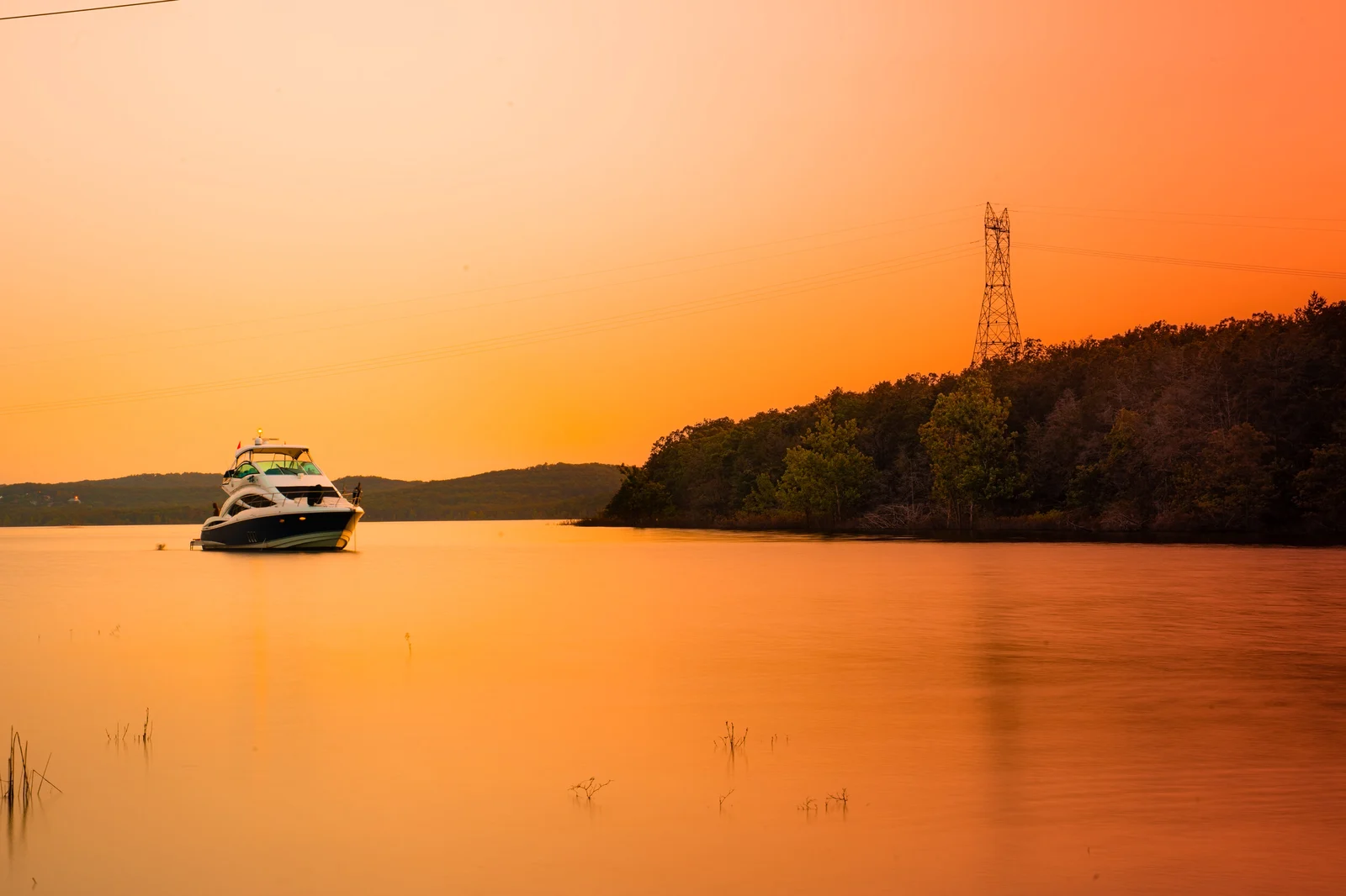 A small boat crossing the water at sunset