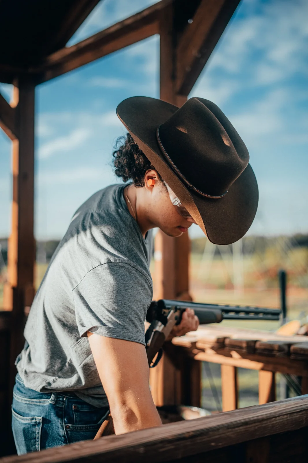 A young shooter in a wide-brimmed hat at a range