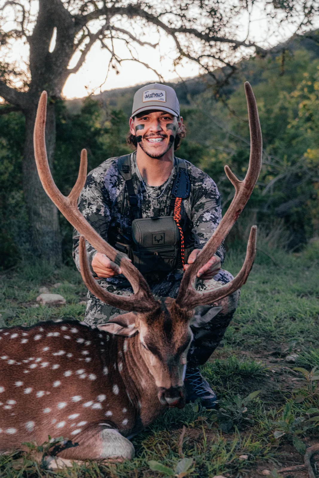 Hunter posing with a deer in the woods